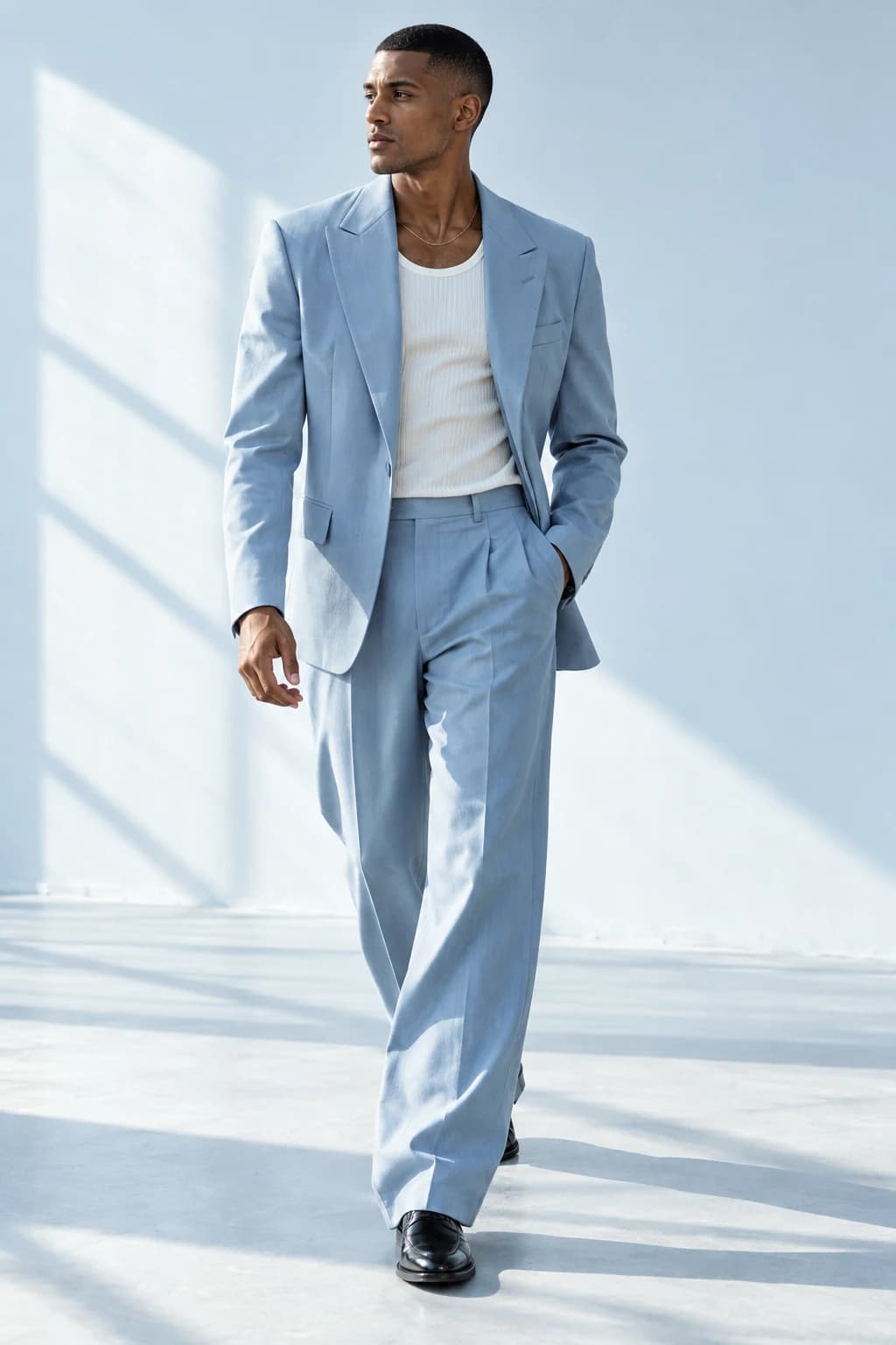 Male model walking in a pale blue suit and white tank top